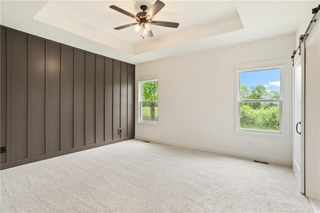 1604 Mulberry St, Pleasant Hill, MO 64080 - unfurnished room with a barn door, a tray ceiling, light colored carpet, and a ceiling fan