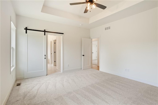 1604 Mulberry St, Pleasant Hill, MO 64080 - unfurnished bedroom with a barn door, carpet floors, a tray ceiling, and baseboards