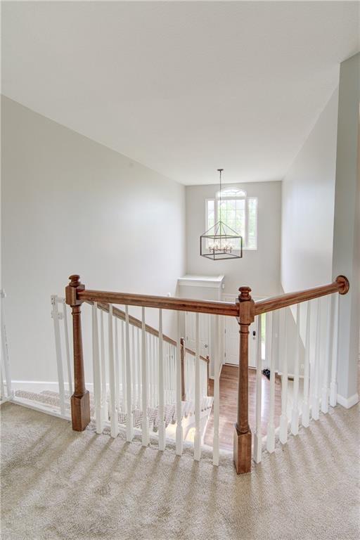 8812 NE 101st St, Kansas City, MO 64157 - stairway with carpet flooring, a chandelier, and baseboards