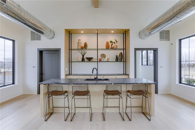 kitchen with light wood-type flooring, visible vents, a breakfast bar area, and a sink