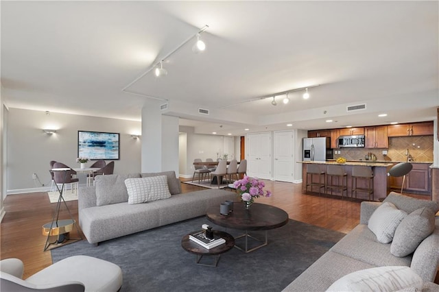 living area with track lighting, dark wood-type flooring, and baseboards