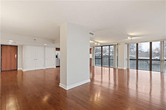 unfurnished living room with track lighting, wood finished floors, and baseboards