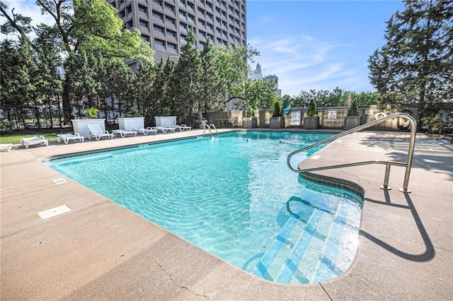 community pool with a patio and fence
