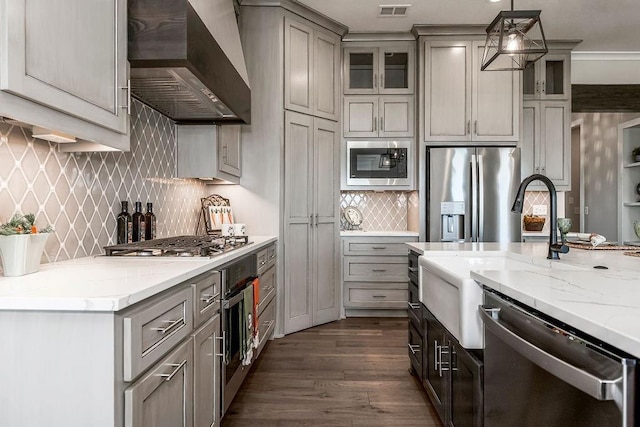 kitchen with stainless steel appliances, wall chimney exhaust hood, dark wood-style flooring, decorative backsplash, and light stone countertops