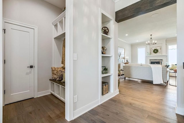 mudroom featuring baseboards, built in shelves, a notable chandelier, and wood finished floors