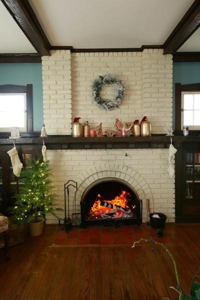 interior space featuring a fireplace, ornamental molding, beamed ceiling, and wood finished floors