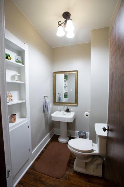 bathroom with toilet, baseboards, a sink, and wood finished floors