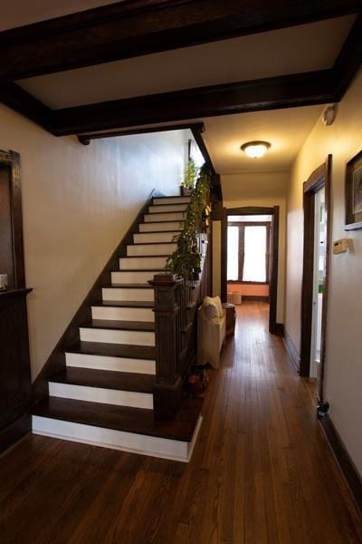 staircase featuring wood finished floors, baseboards, and beamed ceiling