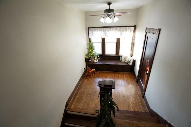 interior space with baseboards, a ceiling fan, and wood finished floors