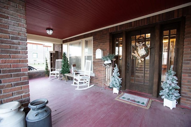 entrance to property with covered porch and brick siding