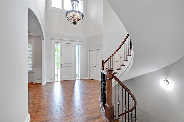24411 W 70th St, Shawnee, KS 66226 - foyer entrance featuring arched walkways, hardwood / wood-style flooring, a towering ceiling, stairway, and a chandelier