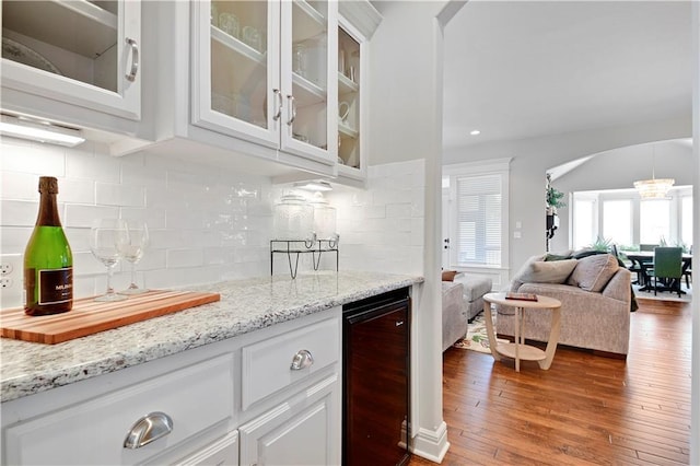 24411 W 70th St, Shawnee, KS 66226 - indoor bar with beverage cooler, arched walkways, dark wood-style floors, and backsplash