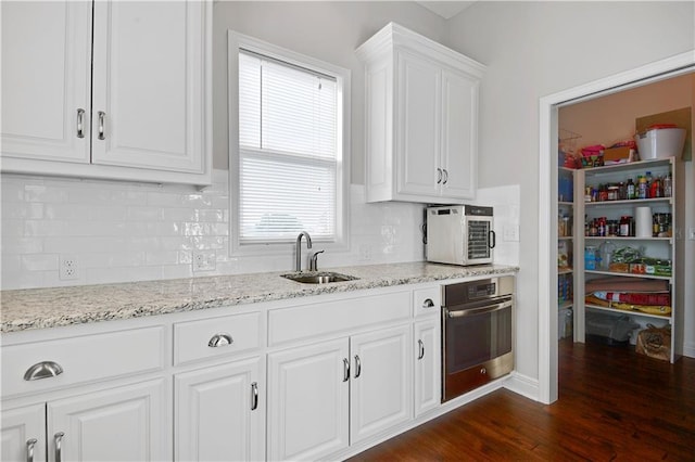 24411 W 70th St, Shawnee, KS 66226 - kitchen with stainless steel oven, a sink, dark wood-type flooring, white cabinetry, and tasteful backsplash