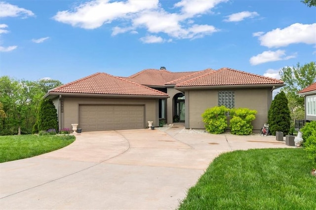 mediterranean / spanish home featuring a tiled roof, an attached garage, a front lawn, and concrete driveway