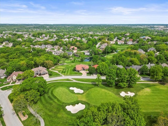 aerial view of property and surrounding area featuring a golf course, nearby suburban area, and a tree filled landscape