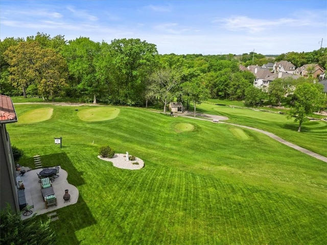 surrounding community with view of golf course, view of wooded area, and a lawn