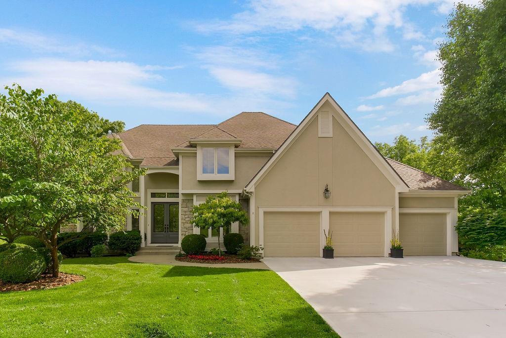 12912 Woodson St, Leawood, KS 66209 - view of front of property featuring french doors, stucco siding, concrete driveway, a garage, and a front yard