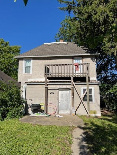 rear view of property with roof with shingles, a garage, and a lawn