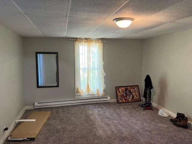 spare room with a paneled ceiling, carpet, baseboards, and a baseboard heating unit