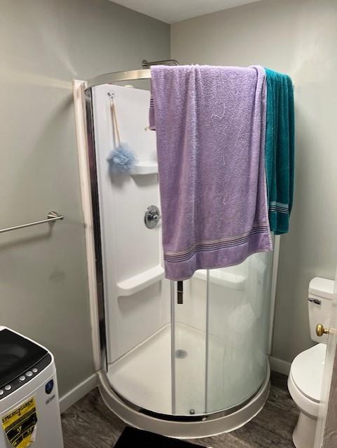 full bath featuring a stall shower, baseboards, toilet, and wood finished floors