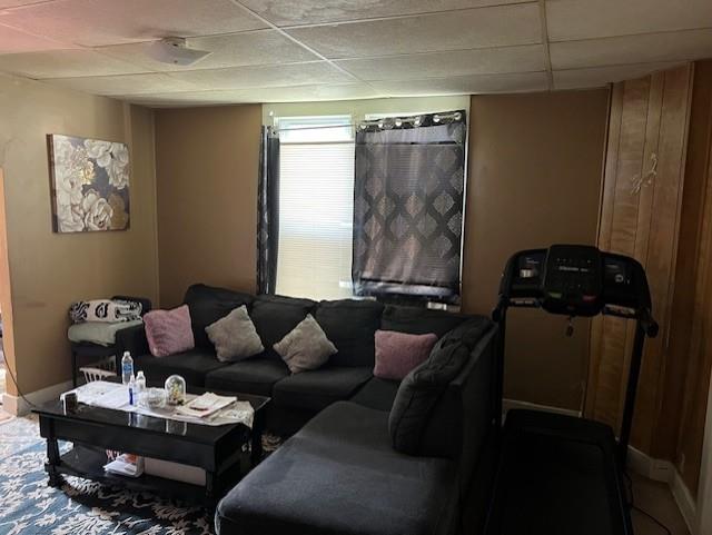 living area with a drop ceiling and baseboards