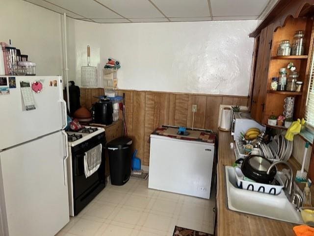kitchen featuring gas range oven, freestanding refrigerator, brown cabinetry, light floors, and fridge