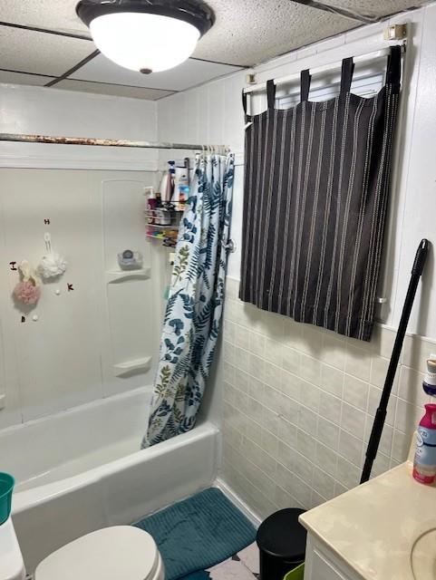 full bathroom featuring shower / tub combo with curtain, vanity, tile walls, and toilet