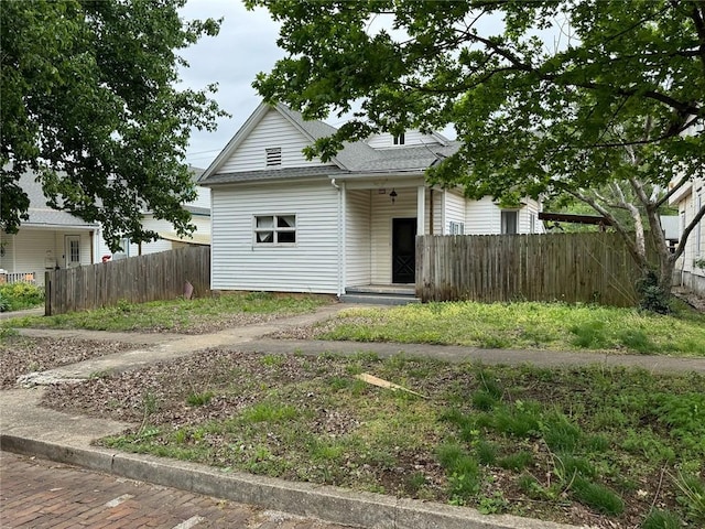 view of front of house with roof with shingles and fence