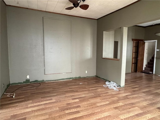 spare room with stairway, ceiling fan, ornamental molding, and wood finished floors