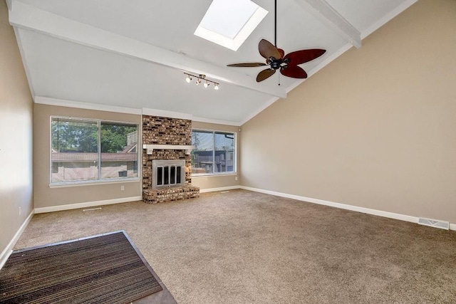 unfurnished living room featuring carpet flooring, a skylight, a fireplace, a ceiling fan, and baseboards