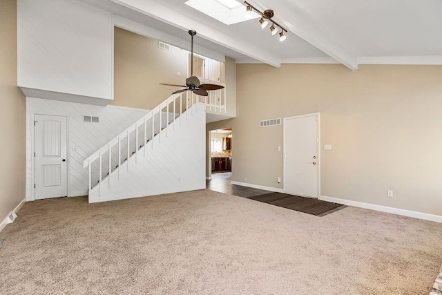 unfurnished living room with carpet floors, stairs, beam ceiling, baseboards, and a towering ceiling