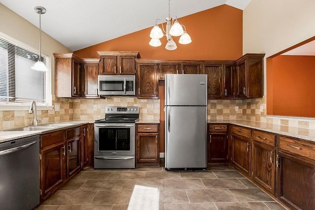 kitchen featuring appliances with stainless steel finishes, a sink, a chandelier, pendant lighting, and decorative backsplash