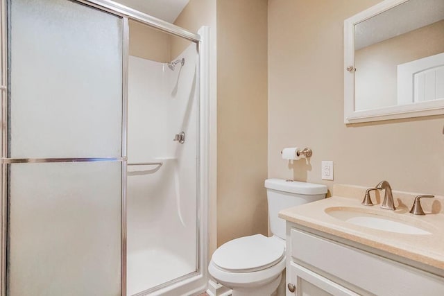 full bathroom featuring a stall shower, toilet, and vanity
