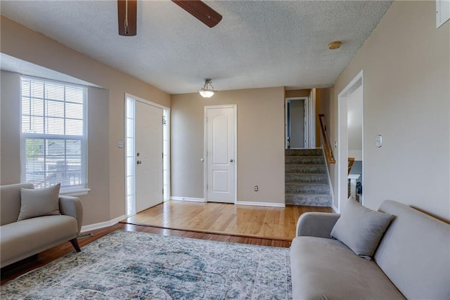 8403 NE 115th Ter, Kansas City, MO 64157 - living room with a textured ceiling, stairs, wood finished floors, a ceiling fan, and baseboards