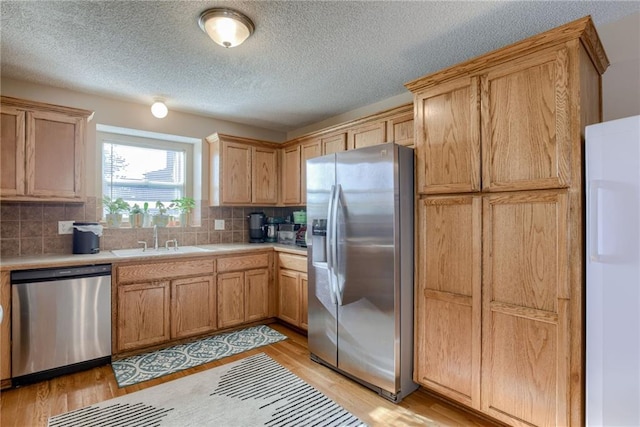 8403 NE 115th Ter, Kansas City, MO 64157 - kitchen with stainless steel appliances, a sink, light countertops, light wood-style floors, and tasteful backsplash
