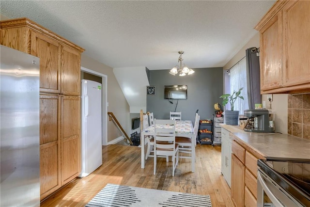 8403 NE 115th Ter, Kansas City, MO 64157 - dining space featuring light wood finished floors, a chandelier, a textured ceiling, and baseboards