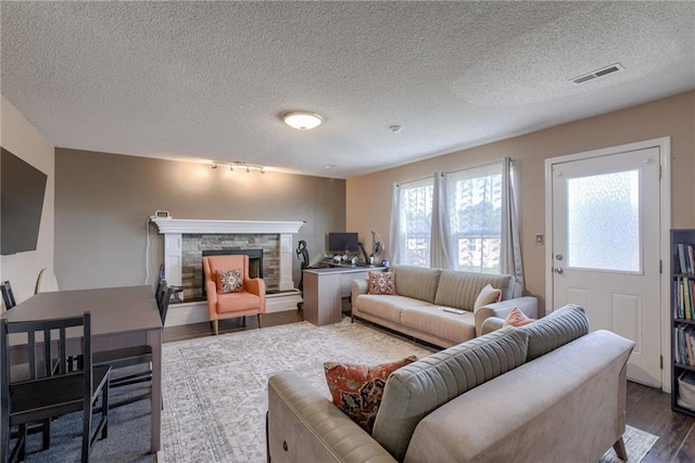 8403 NE 115th Ter, Kansas City, MO 64157 - living area featuring a stone fireplace, dark wood-type flooring, a textured ceiling, and track lighting