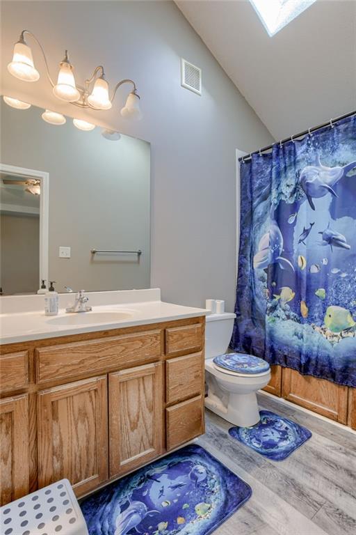 8403 NE 115th Ter, Kansas City, MO 64157 - full bath featuring toilet, vanity, wood finished floors, high vaulted ceiling, and curtained shower