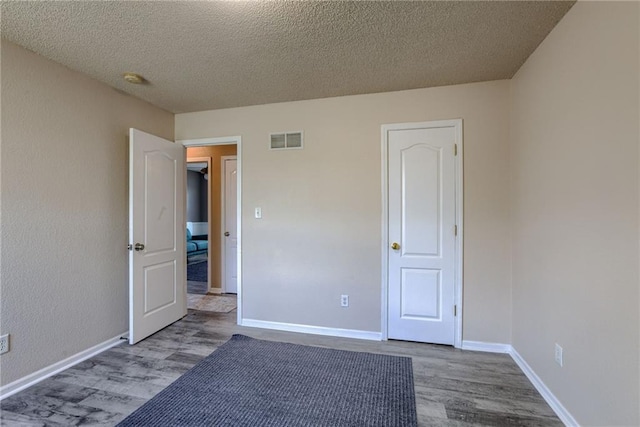 8403 NE 115th Ter, Kansas City, MO 64157 - unfurnished bedroom featuring wood finished floors, a textured ceiling, and baseboards