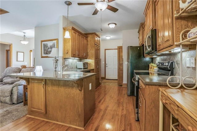 kitchen featuring range with electric stovetop, stainless steel microwave, a breakfast bar, a ceiling fan, and brown cabinets