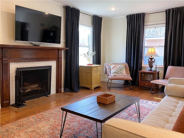 living room with ornamental molding, wood finished floors, a brick fireplace, and recessed lighting