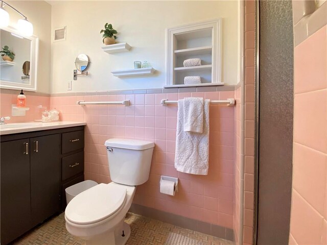 full bath featuring tile walls, toilet, wainscoting, tile patterned floors, and vanity