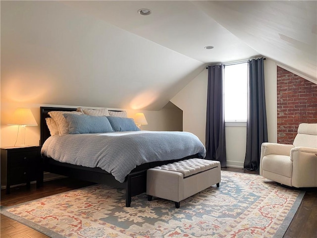 bedroom with wood finished floors and lofted ceiling