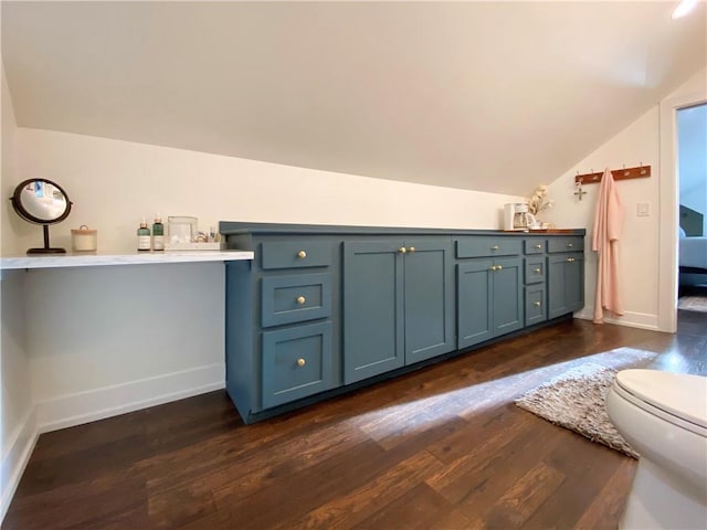 bathroom with lofted ceiling, wood finished floors, baseboards, and toilet
