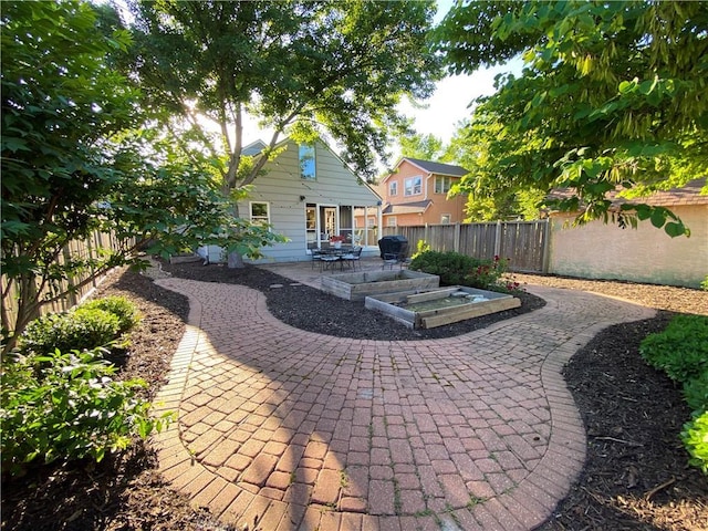 rear view of house with a patio area, a fenced backyard, and a vegetable garden