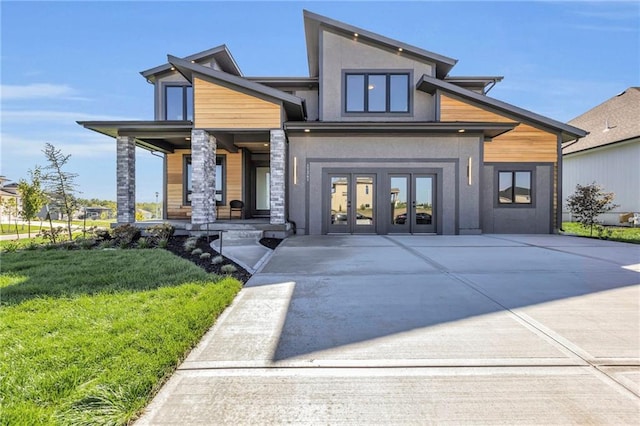 exterior space with a porch, stucco siding, french doors, and a lawn