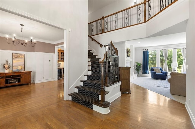 8701 W 157th St, Overland Park, KS 66221 - stairs featuring wood finished floors, a high ceiling, a chandelier, a decorative wall, and crown molding
