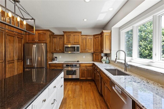 8701 W 157th St, Overland Park, KS 66221 - kitchen with stainless steel appliances, a sink, dark wood-type flooring, light stone countertops, and decorative backsplash