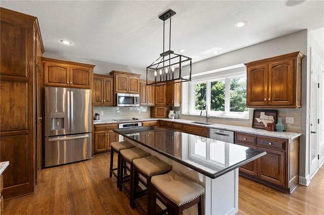 8701 W 157th St, Overland Park, KS 66221 - kitchen featuring stainless steel appliances, a sink, dark wood finished floors, tasteful backsplash, and a kitchen bar