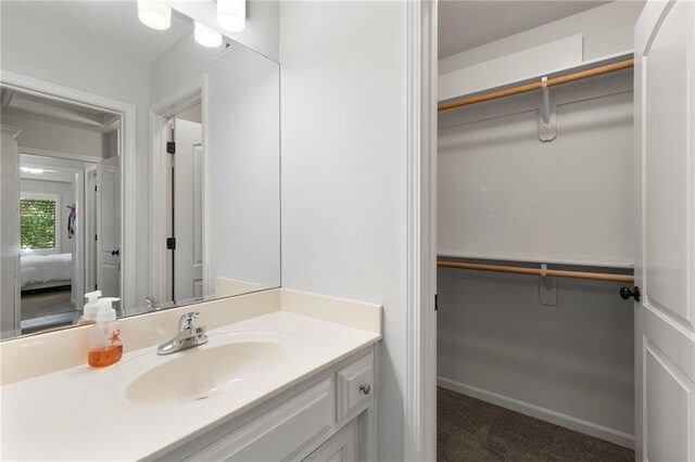 8701 W 157th St, Overland Park, KS 66221 - bathroom featuring vanity, ensuite bath, a walk in closet, and baseboards
